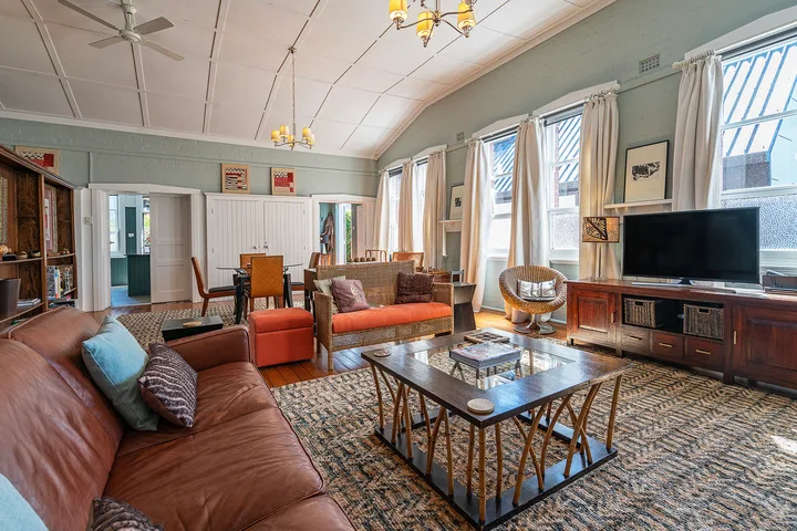 A spacious living room with seating, a coffee table, and a television.