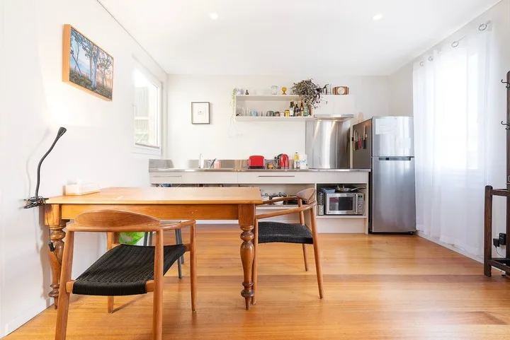A bright kitchen and dining area with a wooden table and stainless steel appliances.