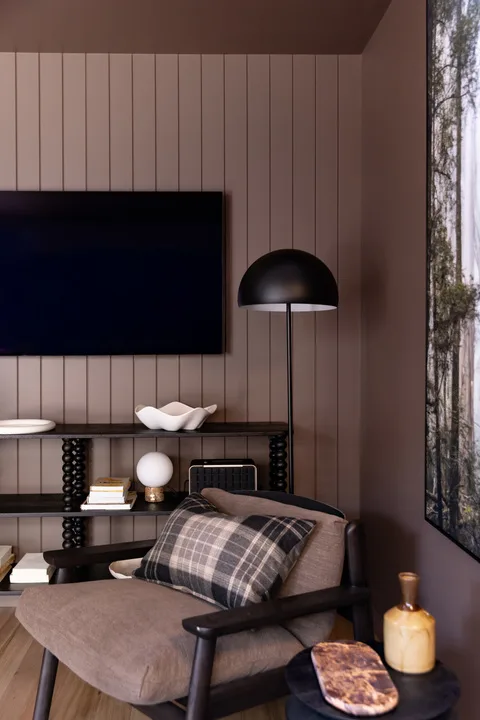 A living room seating area with a television, floor lamp, and plaid cushion.