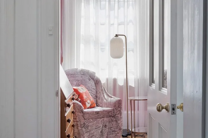 A sitting area with an upholstered chair, a small table, and sheer curtains.