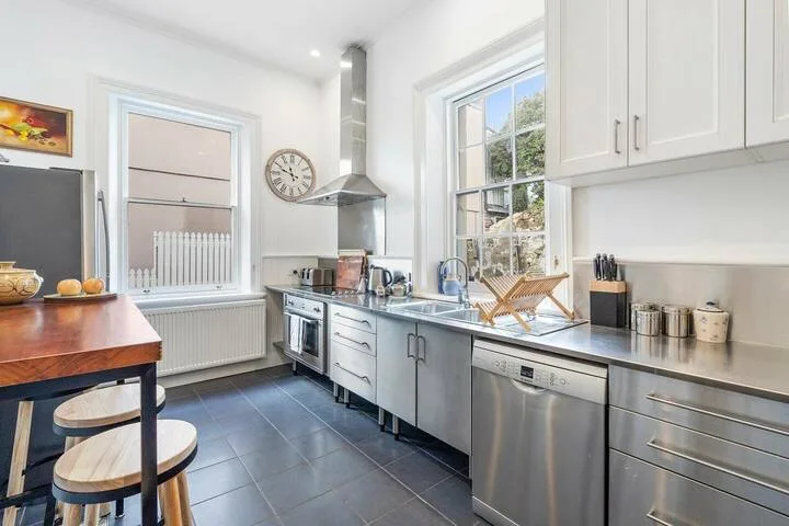 A bright kitchen with stainless-steel appliances and a large window.