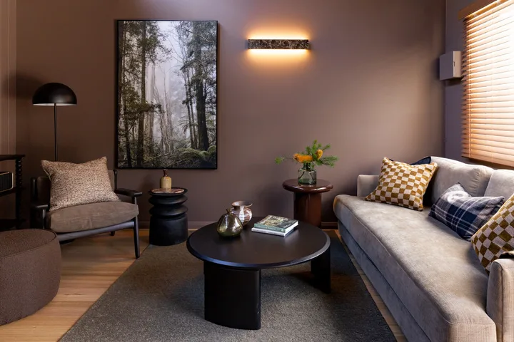 A living room with seating arranged around a coffee table and framed forest artwork.