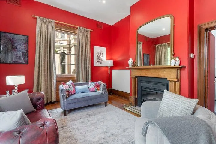 A living room with red walls, seating, and a fireplace.