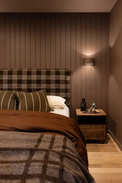 A bedroom with a bed, plaid bedding, and a bedside table.