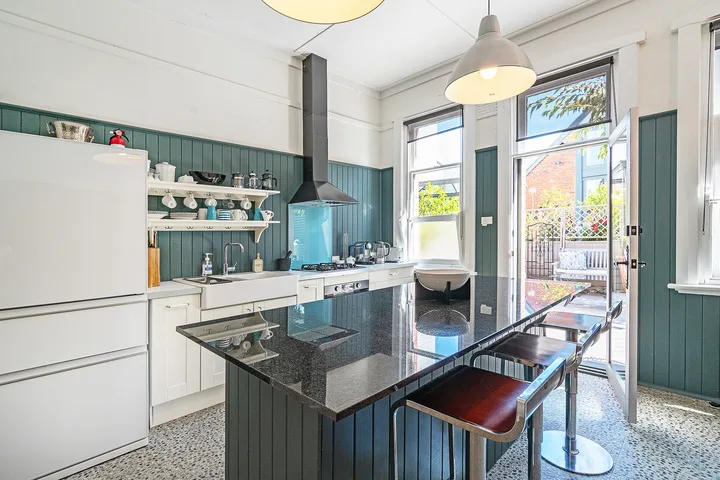 Una cocina luminosa con una isla central y una puerta abierta al patio.