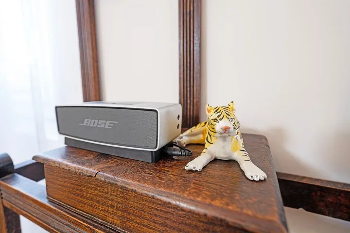 A wooden dresser holds a speaker and a small tiger figurine.