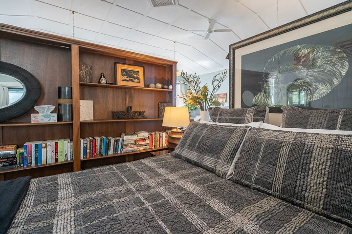 A bedroom with a patterned bed in front of a wooden bookcase.