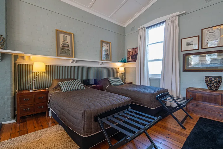 A bedroom with two beds, bedside lamps, and a window with curtains.