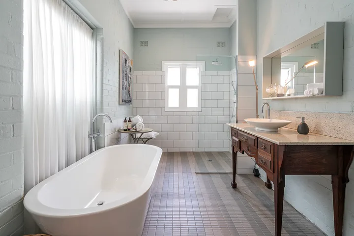 A bright bathroom with a freestanding bathtub, tiled walls, and a wooden vanity.
