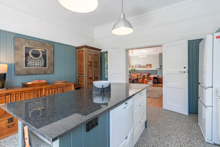 A kitchen with a large island and an open doorway leading to a dining area.