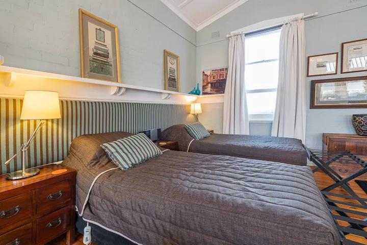 A bedroom with two beds, striped wall paneling, and a bright window.