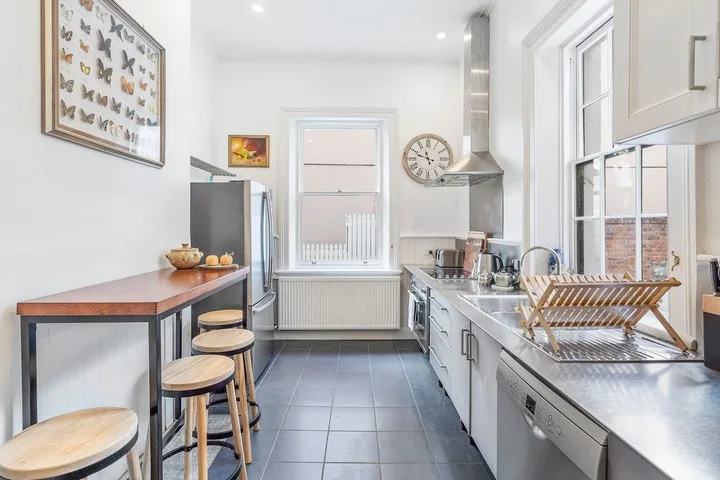 A bright kitchen with a long countertop and stools along the side.