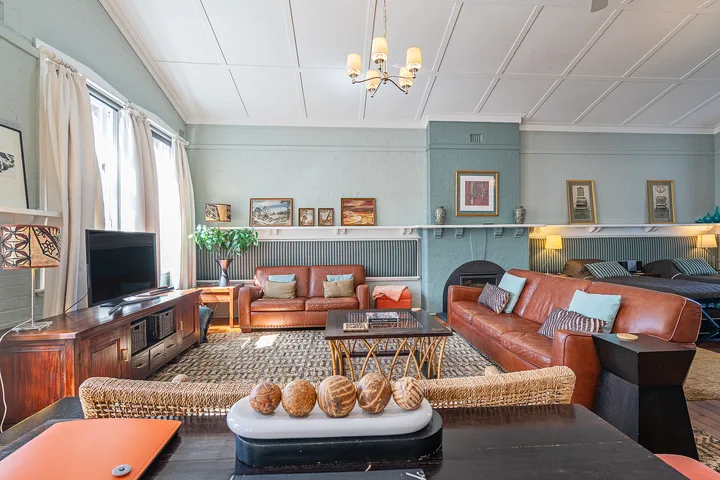 A spacious living room with seating arranged around a patterned rug and coffee table.