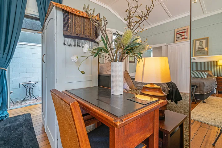 A dining area with a wooden table, chairs, and a vase of flowers.