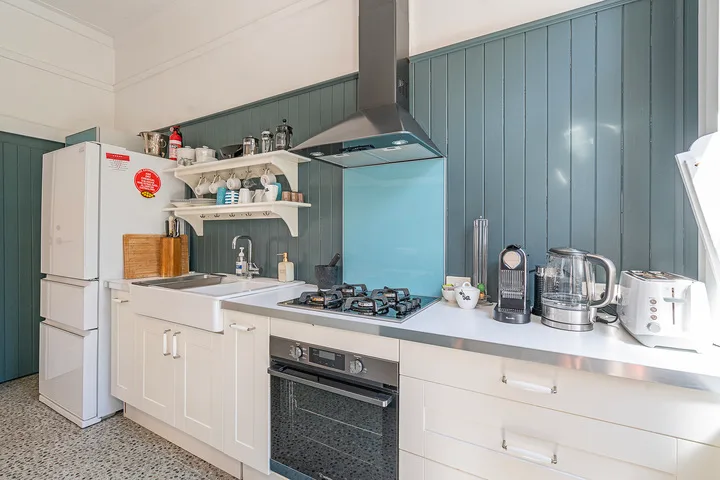 A kitchen with white cabinets, a cooktop, and countertop appliances.