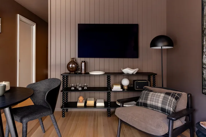 A living room with a wall-mounted television and seating around a console table.