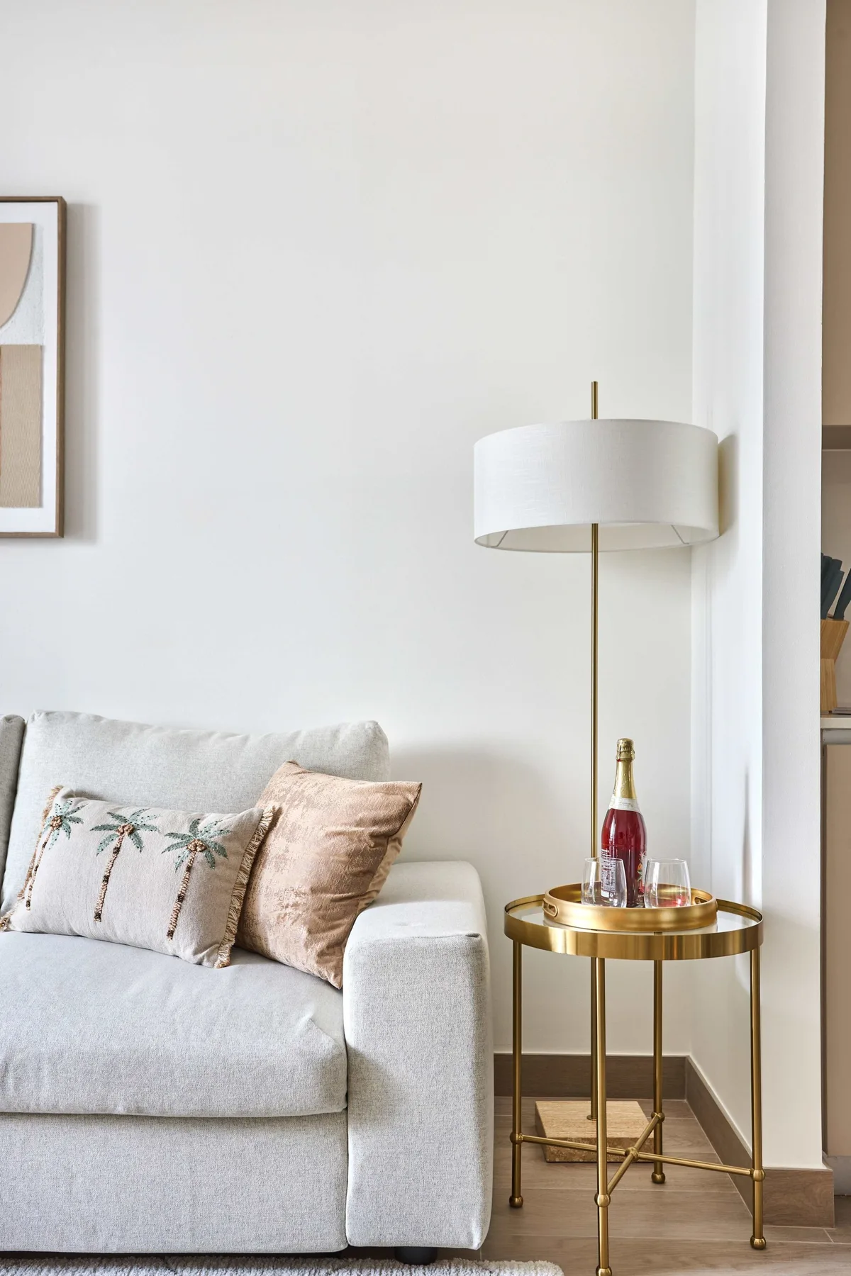 A bright living room with a light-colored sofa and a floor lamp beside a small table.