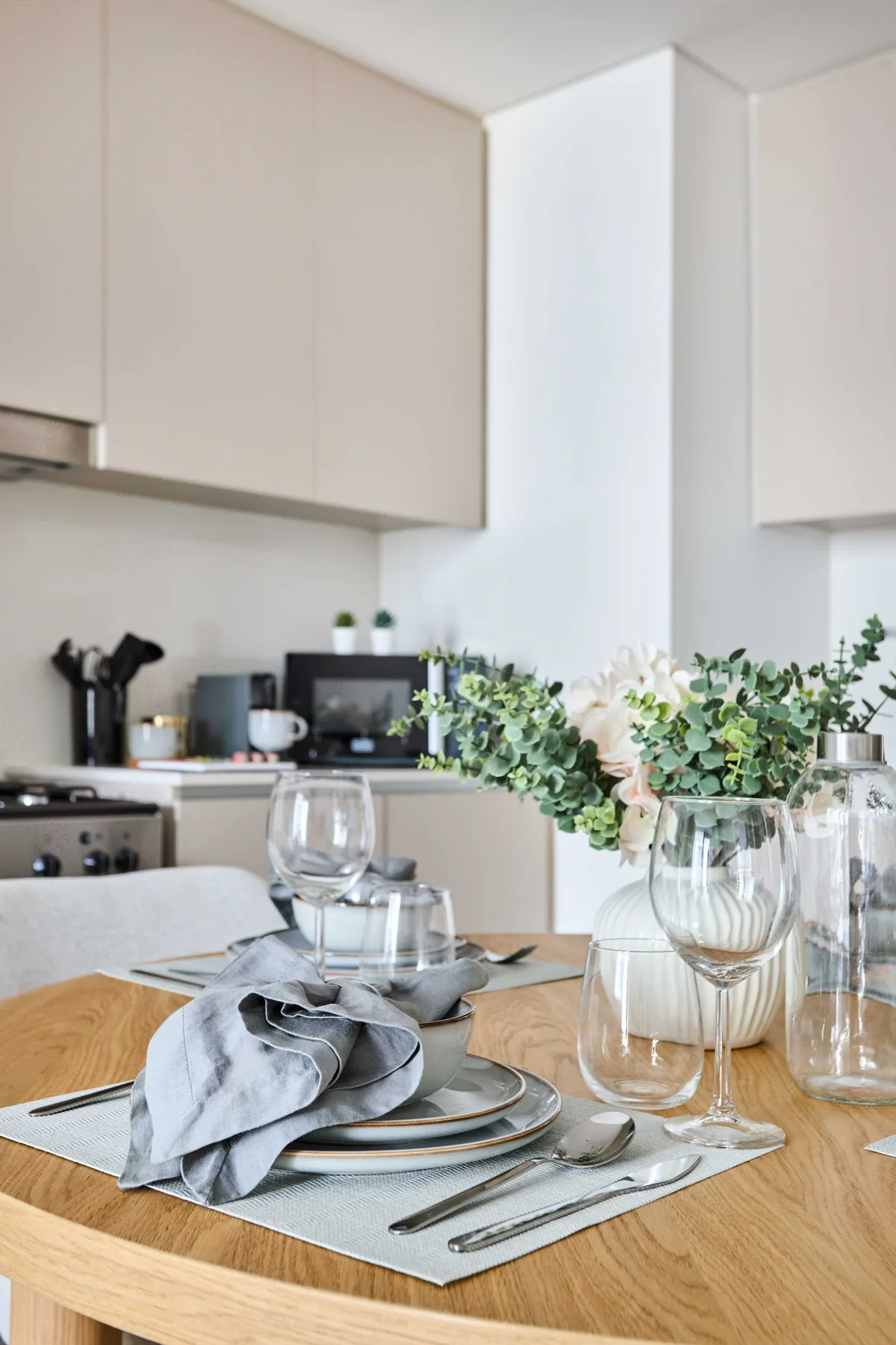 A dining table set with plates and glassware sits in a bright kitchen.
