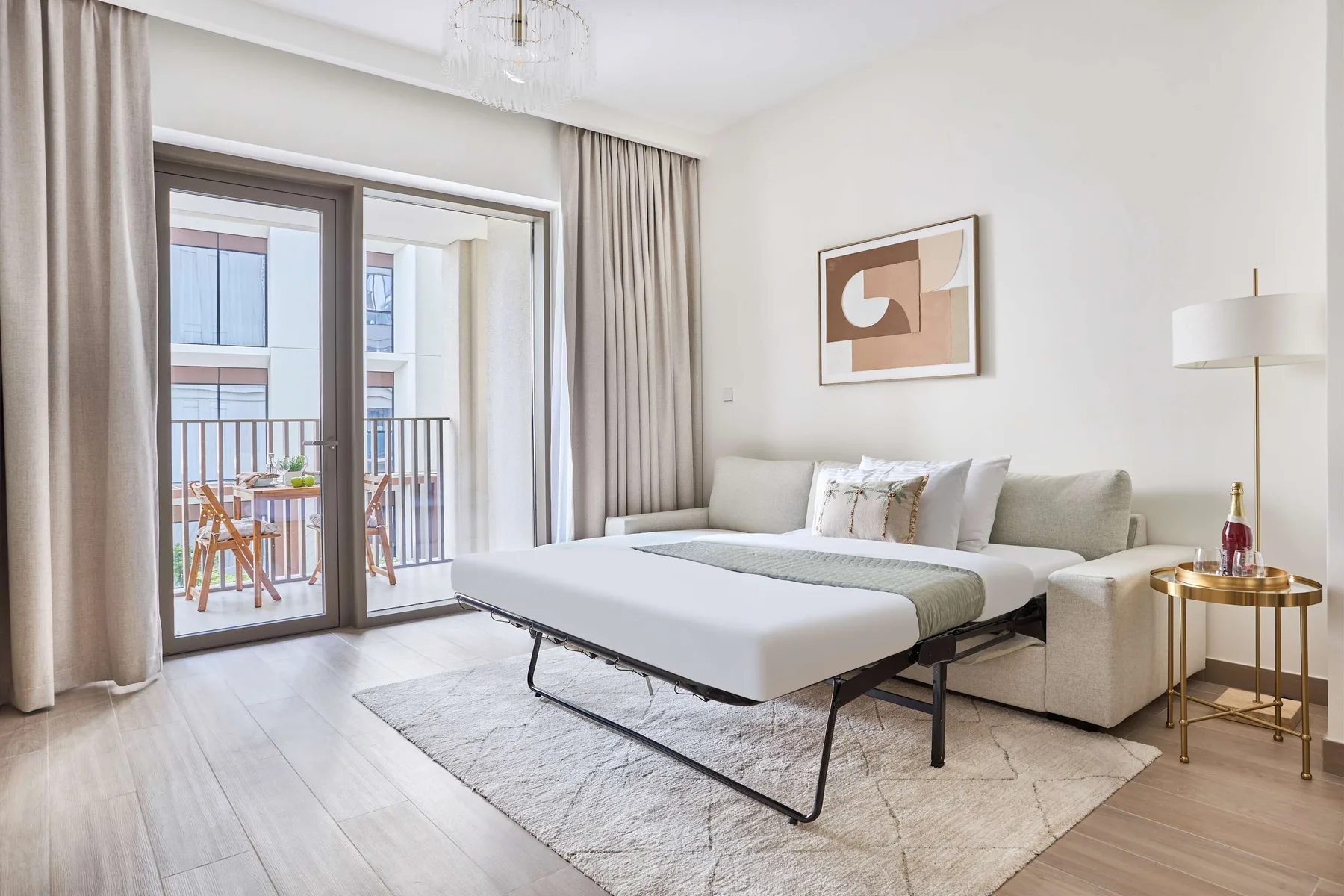 A bright living area with a sofa, a low table, and glass doors opening to a balcony.