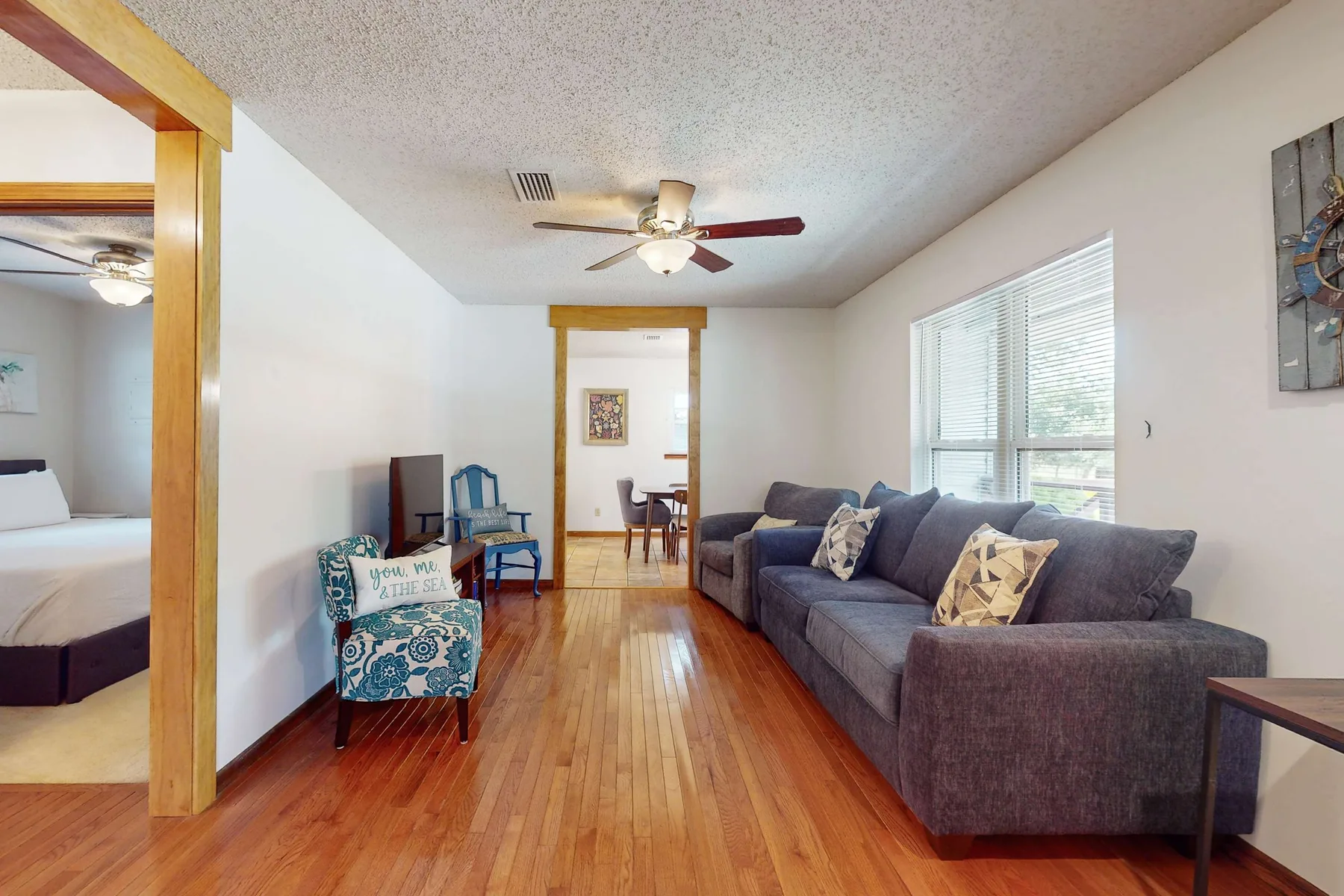 Una sala de estar con asientos junto a ventanas grandes y piso de madera.