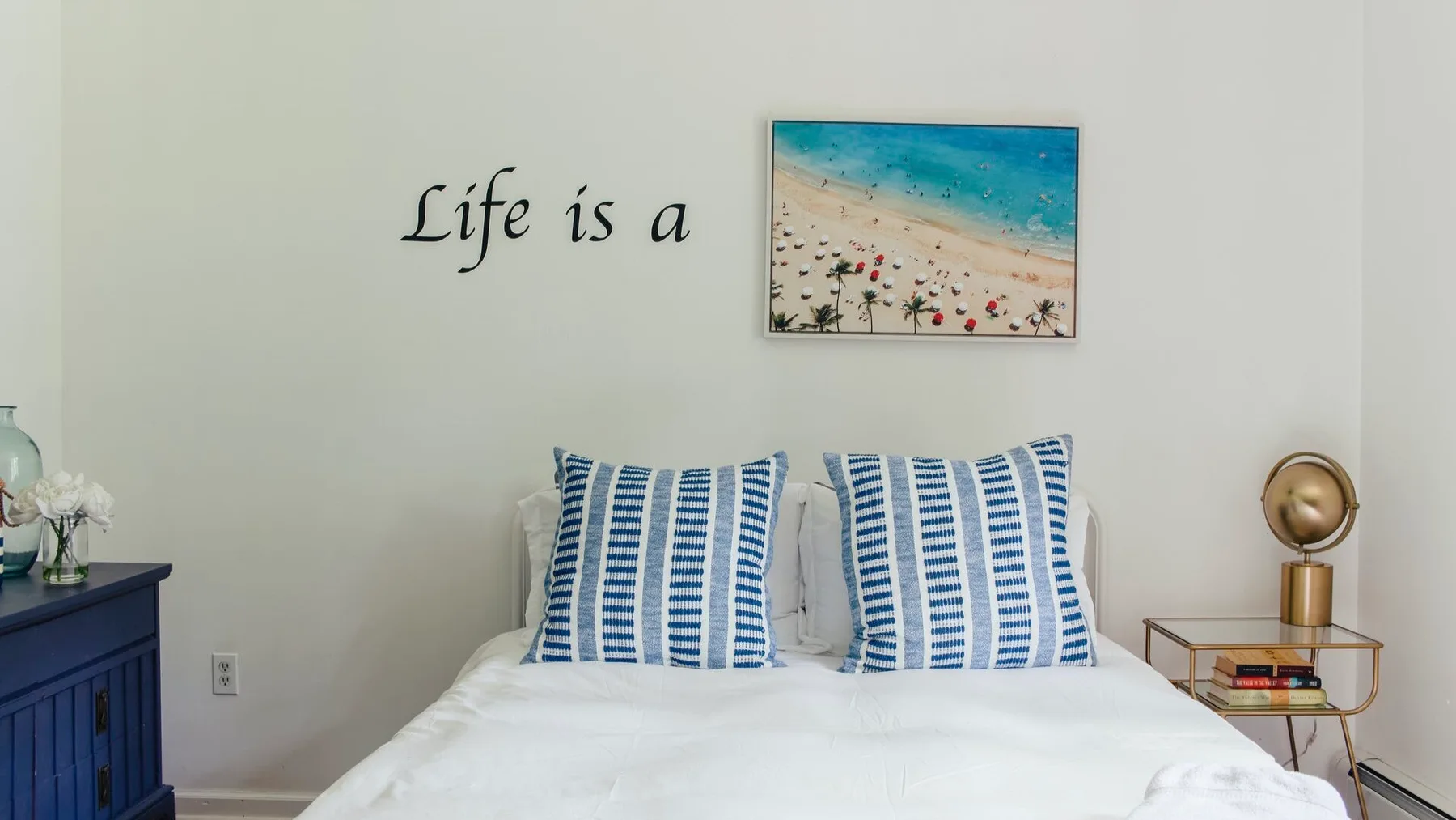 Un dormitorio con una cama bien tendida y almohadas con estampado azul.
