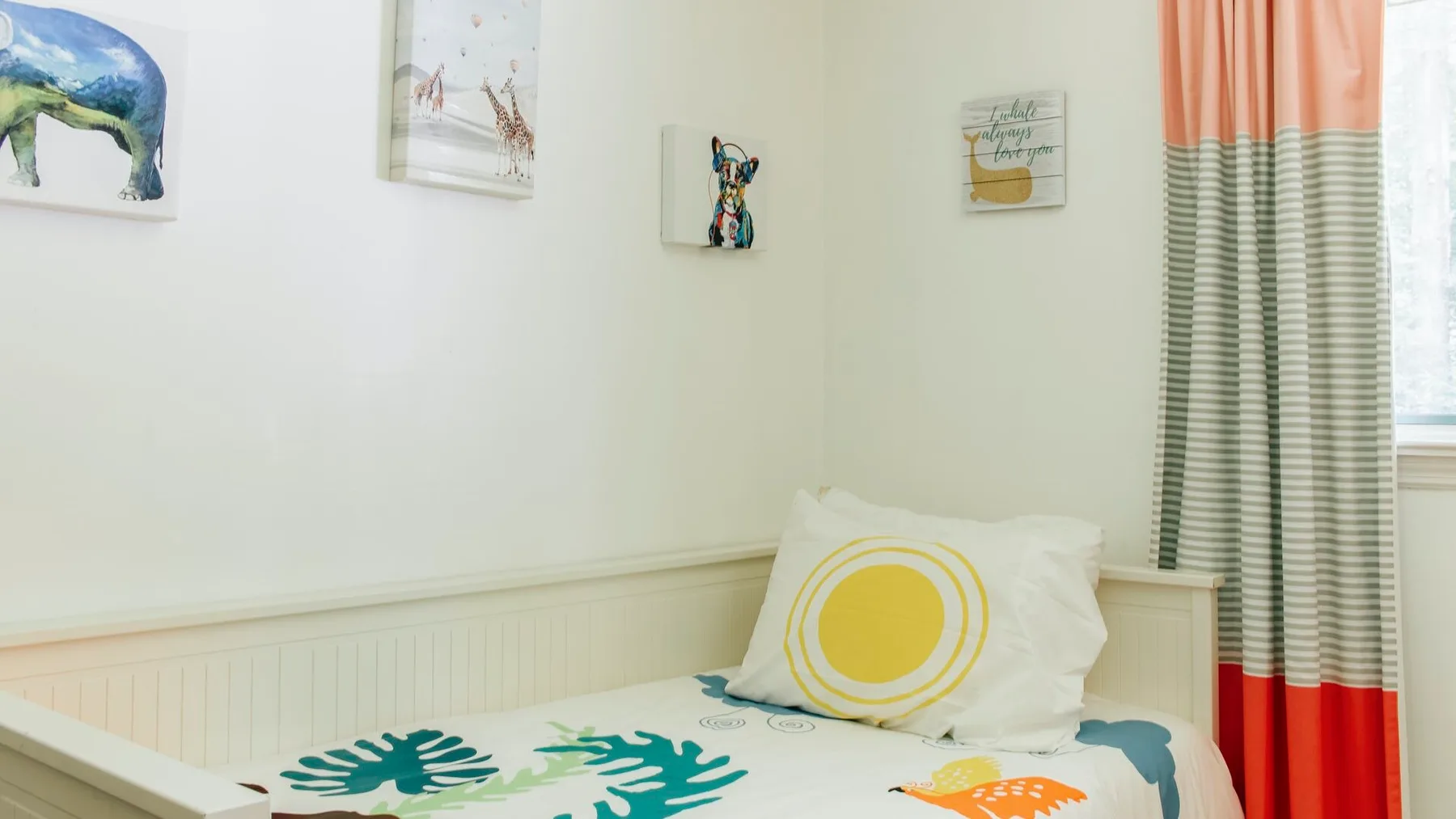 Un dormitorio con una cama, ropa de cama estampada y cuadros coloridos.