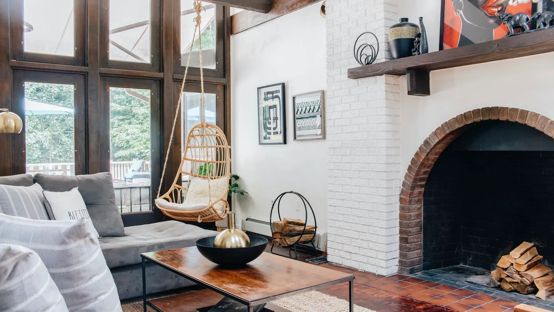Una sala de estar con un asiento colgante, mesa de centro y chimenea de ladrillo.