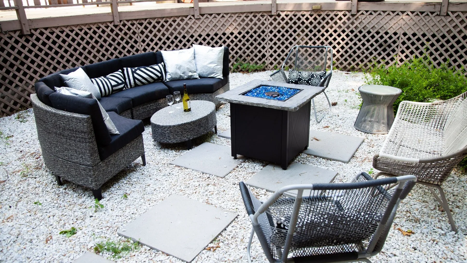 Una zona de estar en un patio de grava con muebles acolchados y una mesa baja.