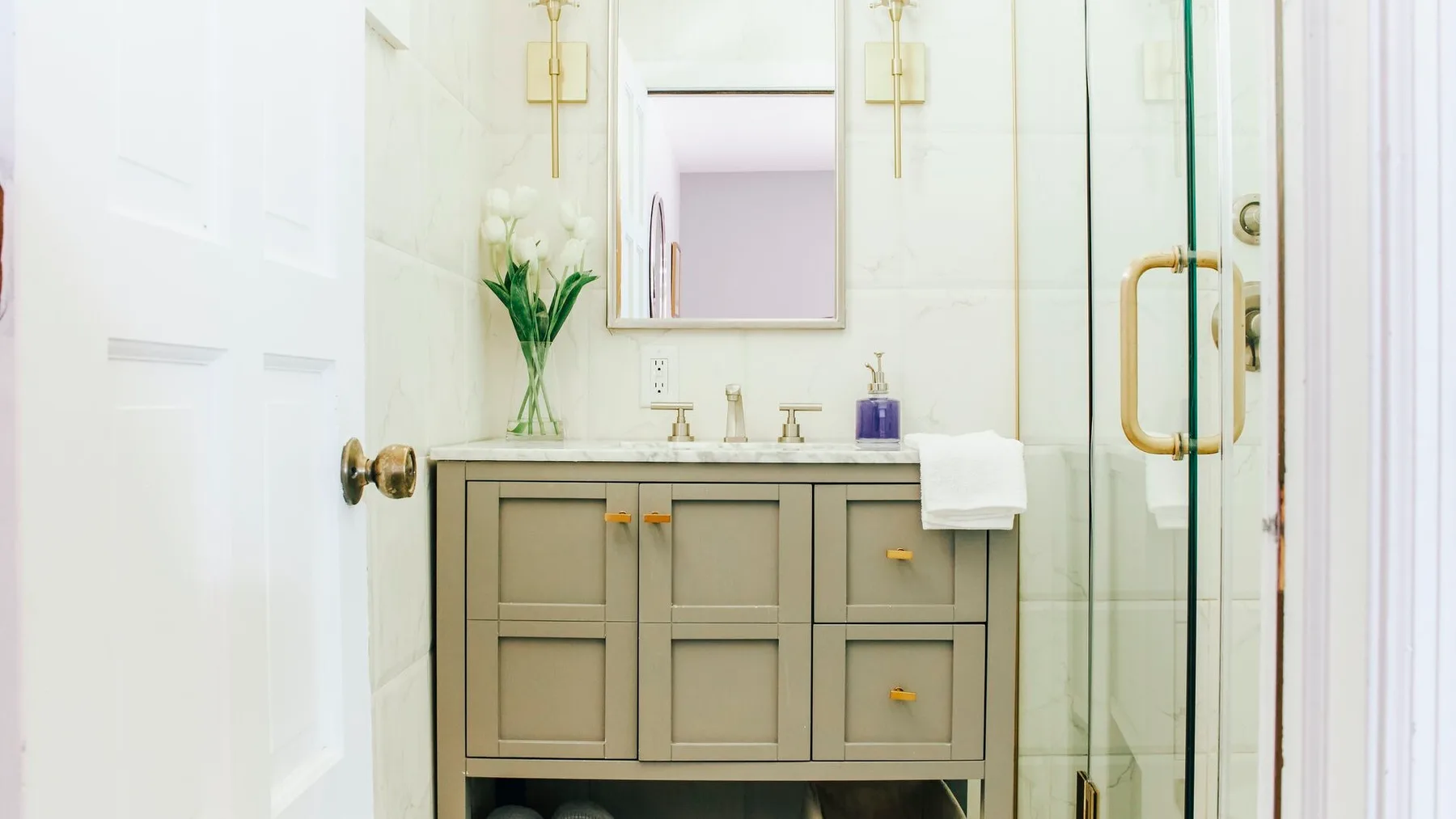 Un baño luminoso con lavabo, espejo y ducha de vidrio.