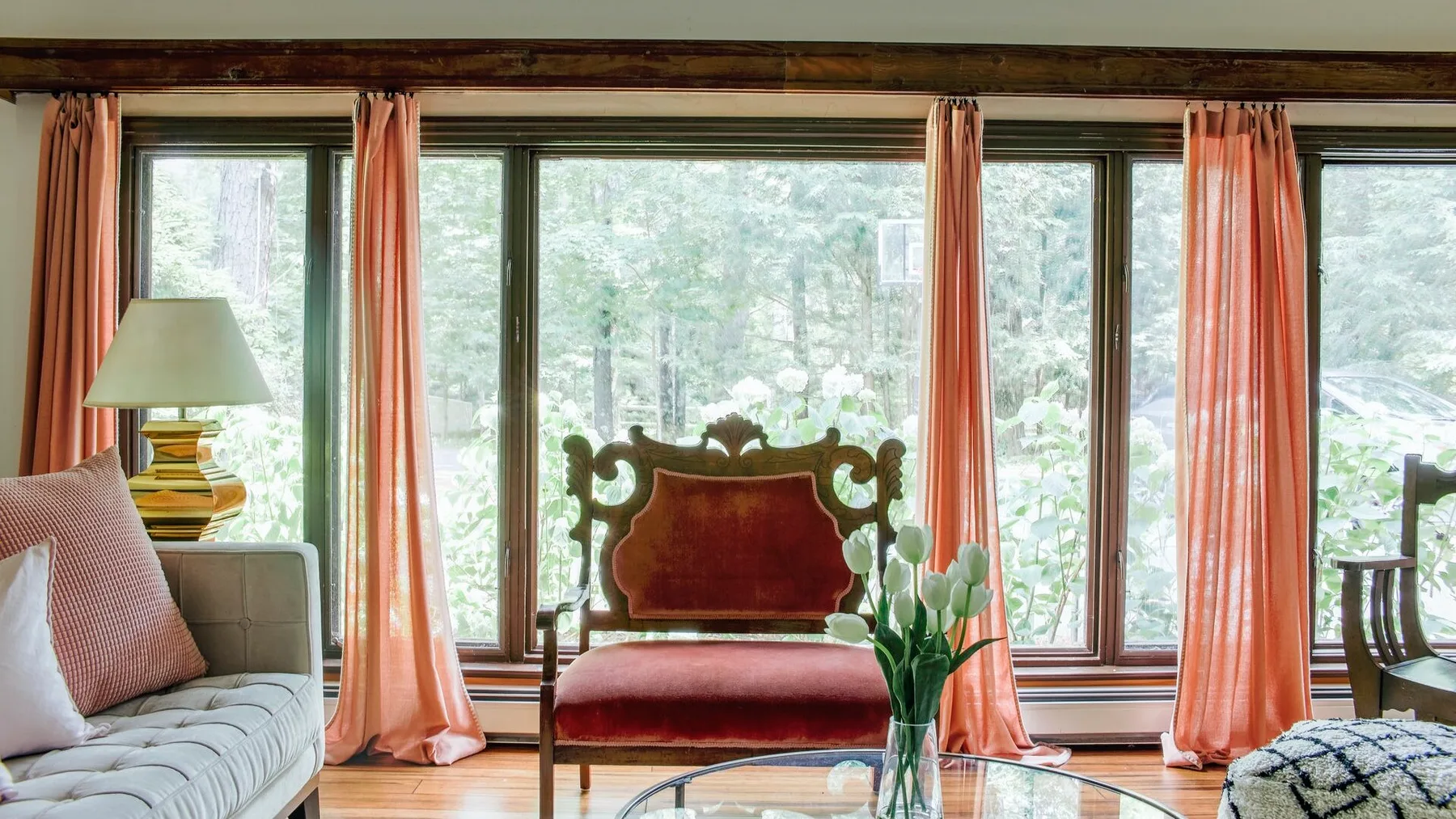 Una sala luminosa con asientos junto a grandes ventanas y cortinas coral.