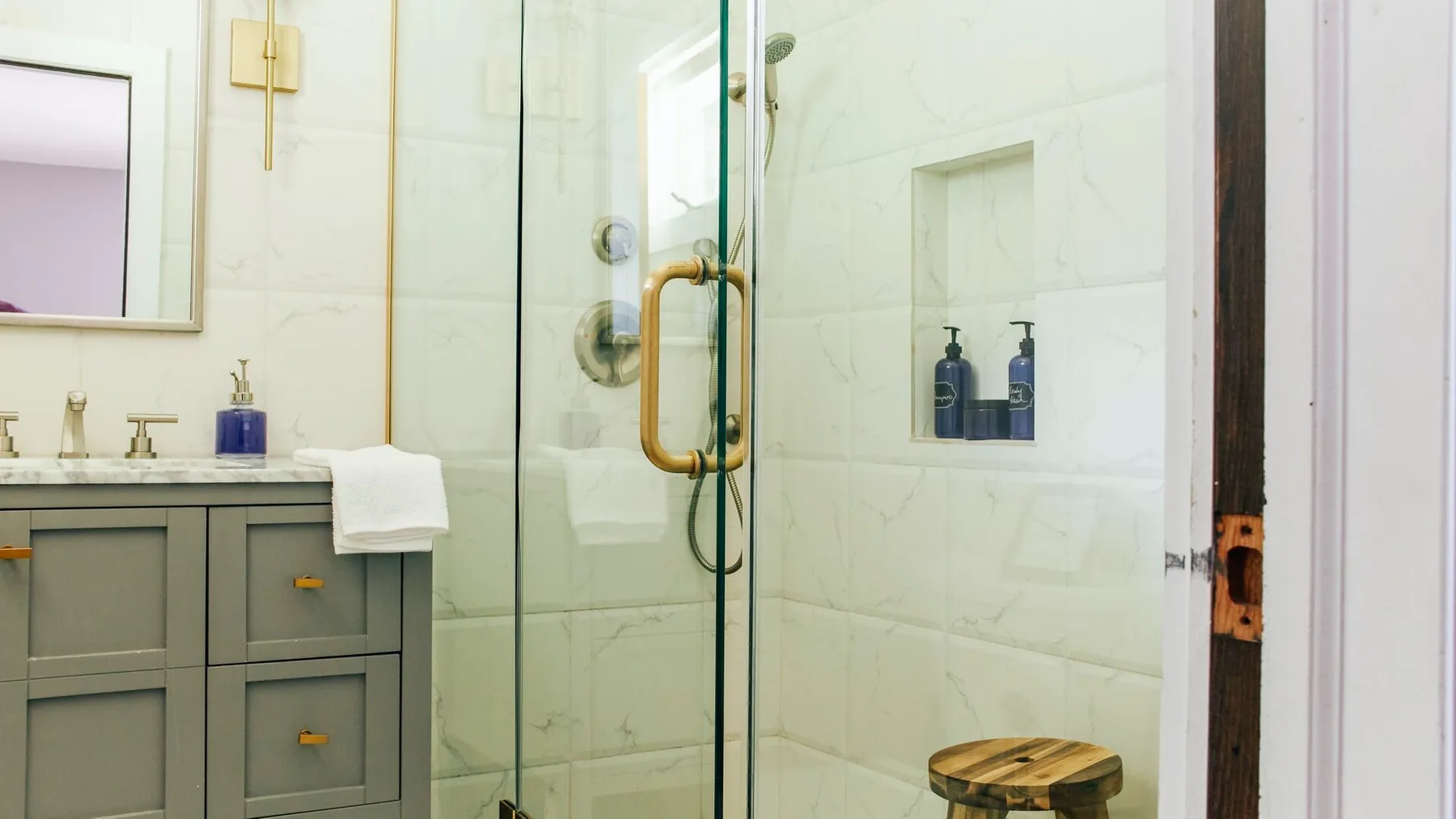 Un baño alicatado con una ducha de vidrio y un tocador.