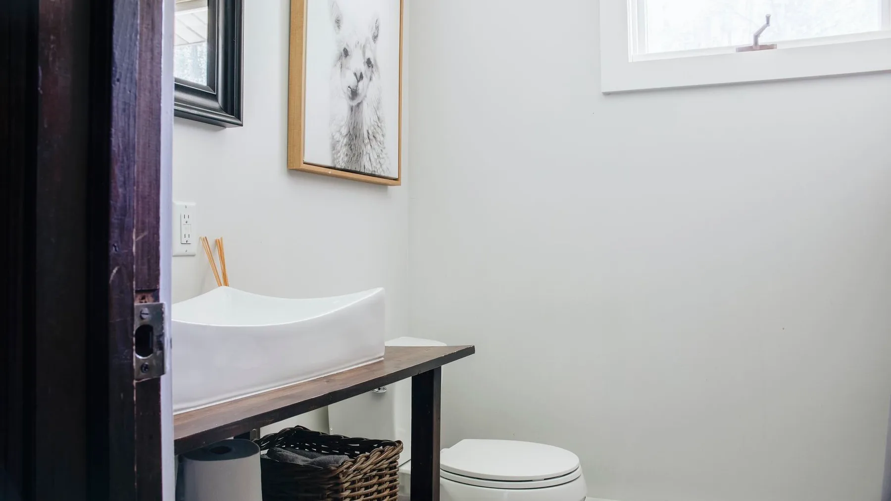 Un baño pequeño con un lavabo de sobreponer, un inodoro y arte enmarcado.