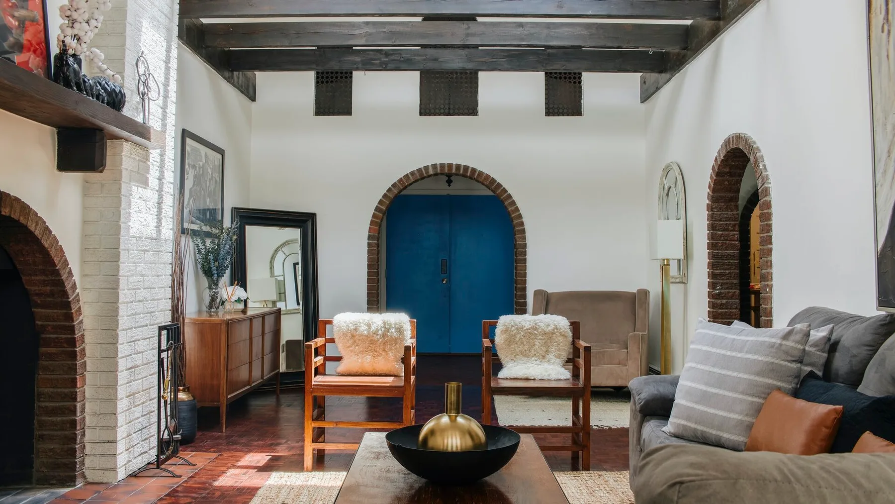 Una sala de estar con una puerta azul arqueada y asientos alrededor de una mesa de centro.
