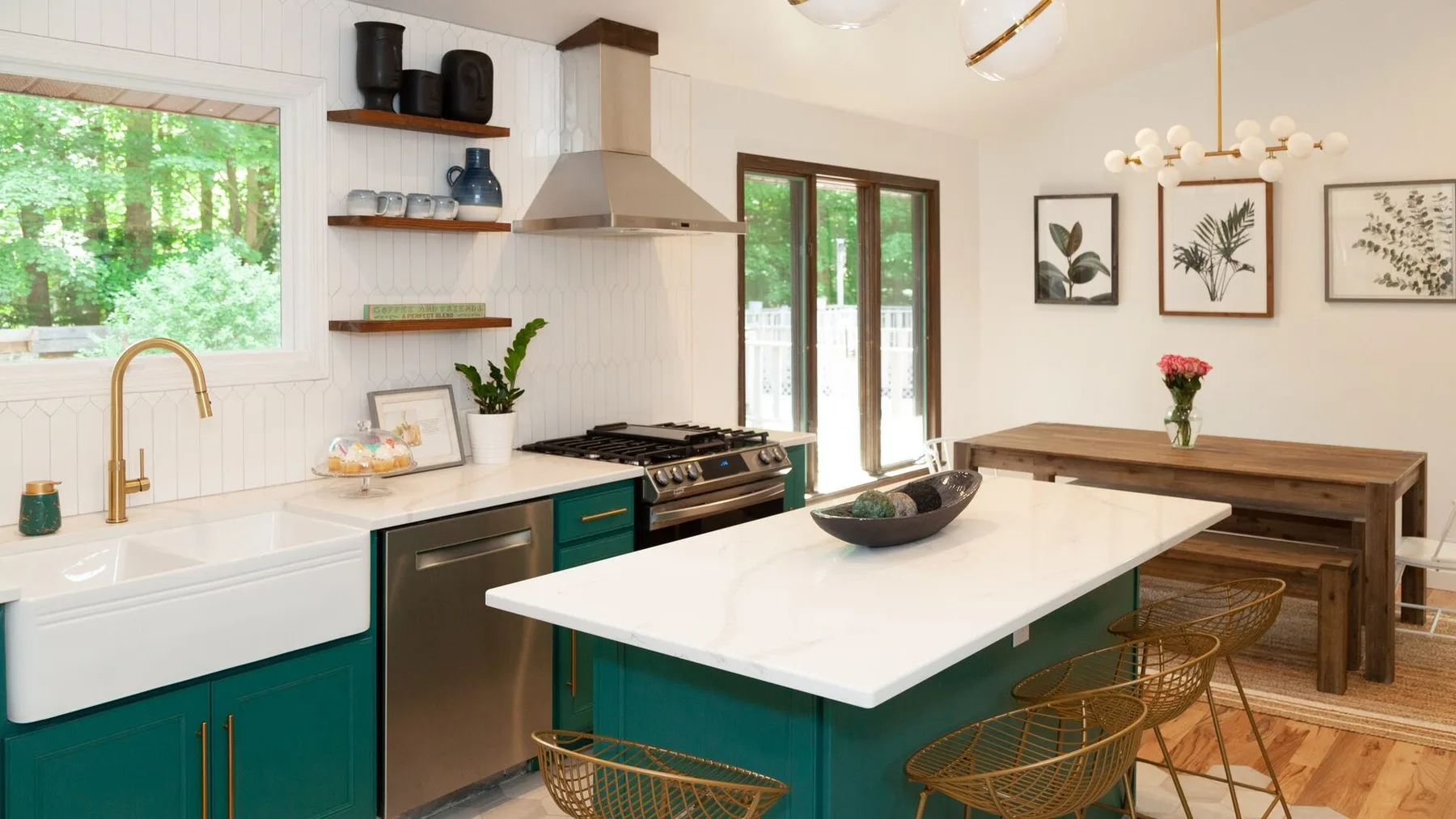 Una cocina luminosa con una isla grande, gabinetes verdes y ventanas con vista a los árboles.