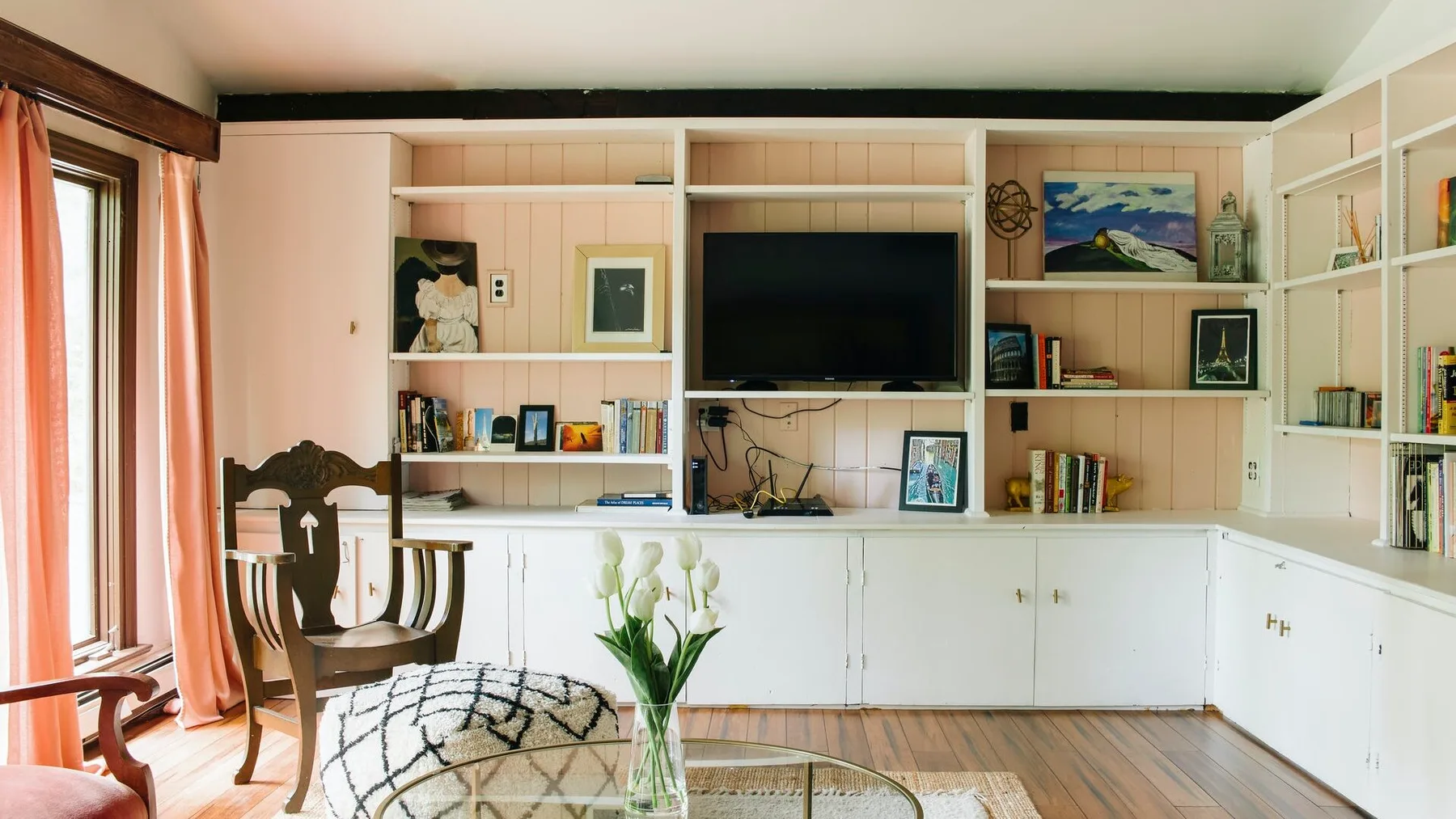 Una sala luminosa con estanterías empotradas, un televisor y asientos.