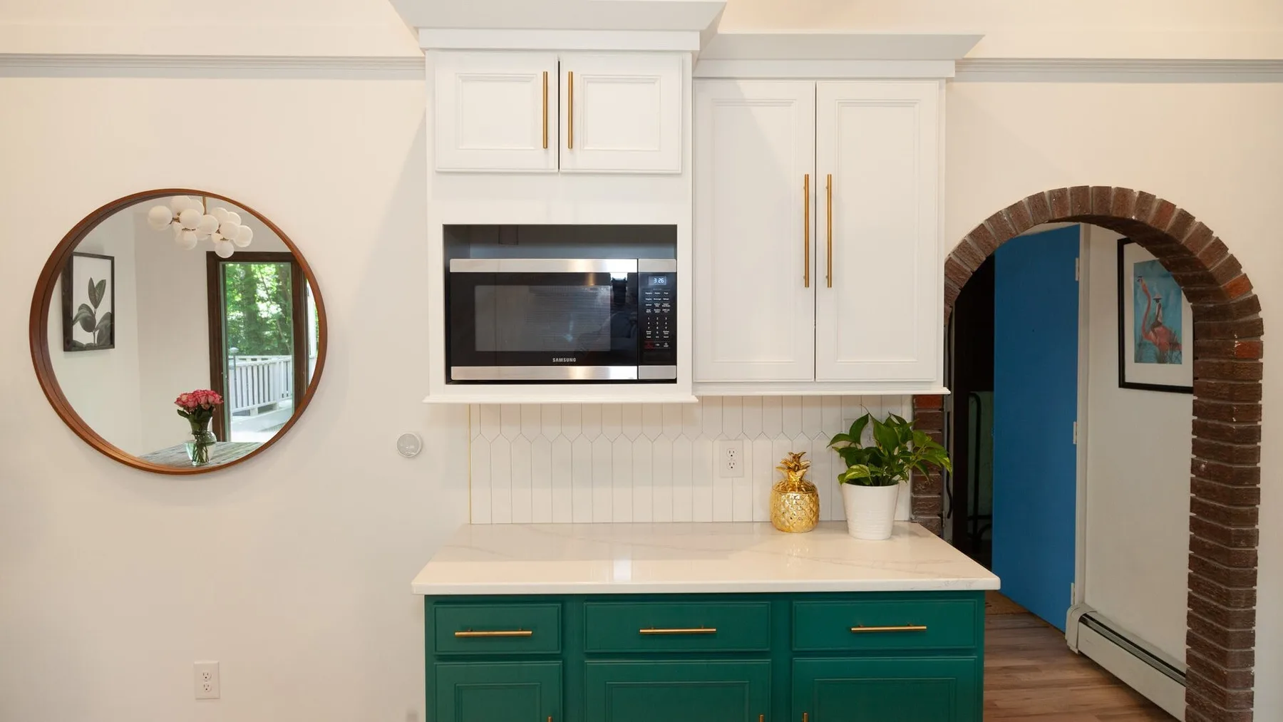 Una cocina luminosa con gabinetes blancos sobre gabinetes verdes y una encimera.