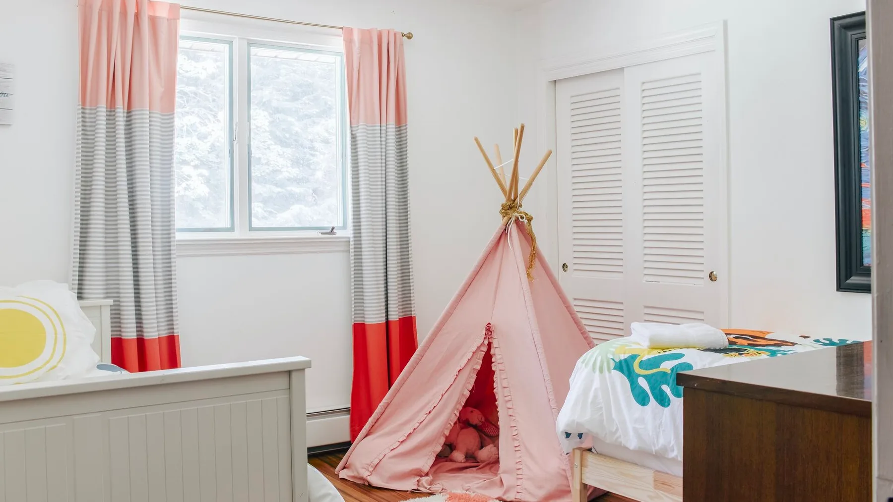 Un dormitorio luminoso con una tienda de tela rosa junto a una cama.