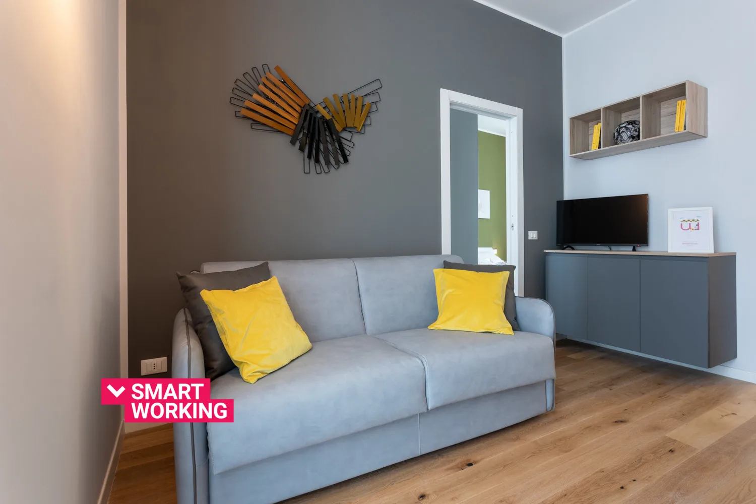 Una sala de estar moderna con un sofá gris y cojines amarillos.