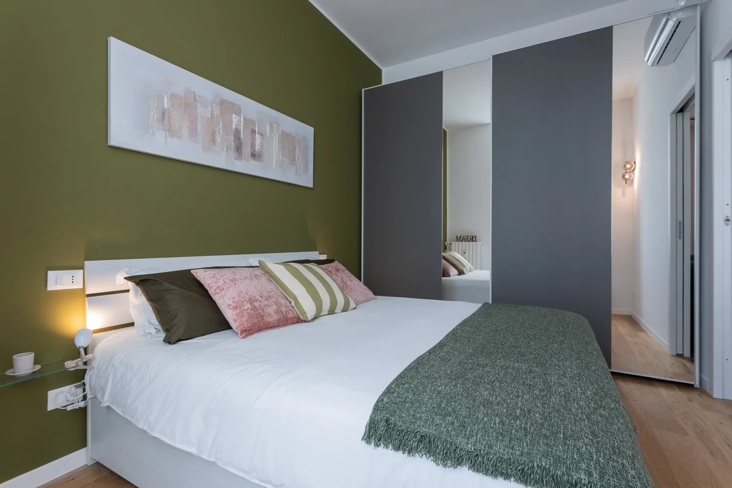 Un dormitorio con una cama arreglada y una pared verde.