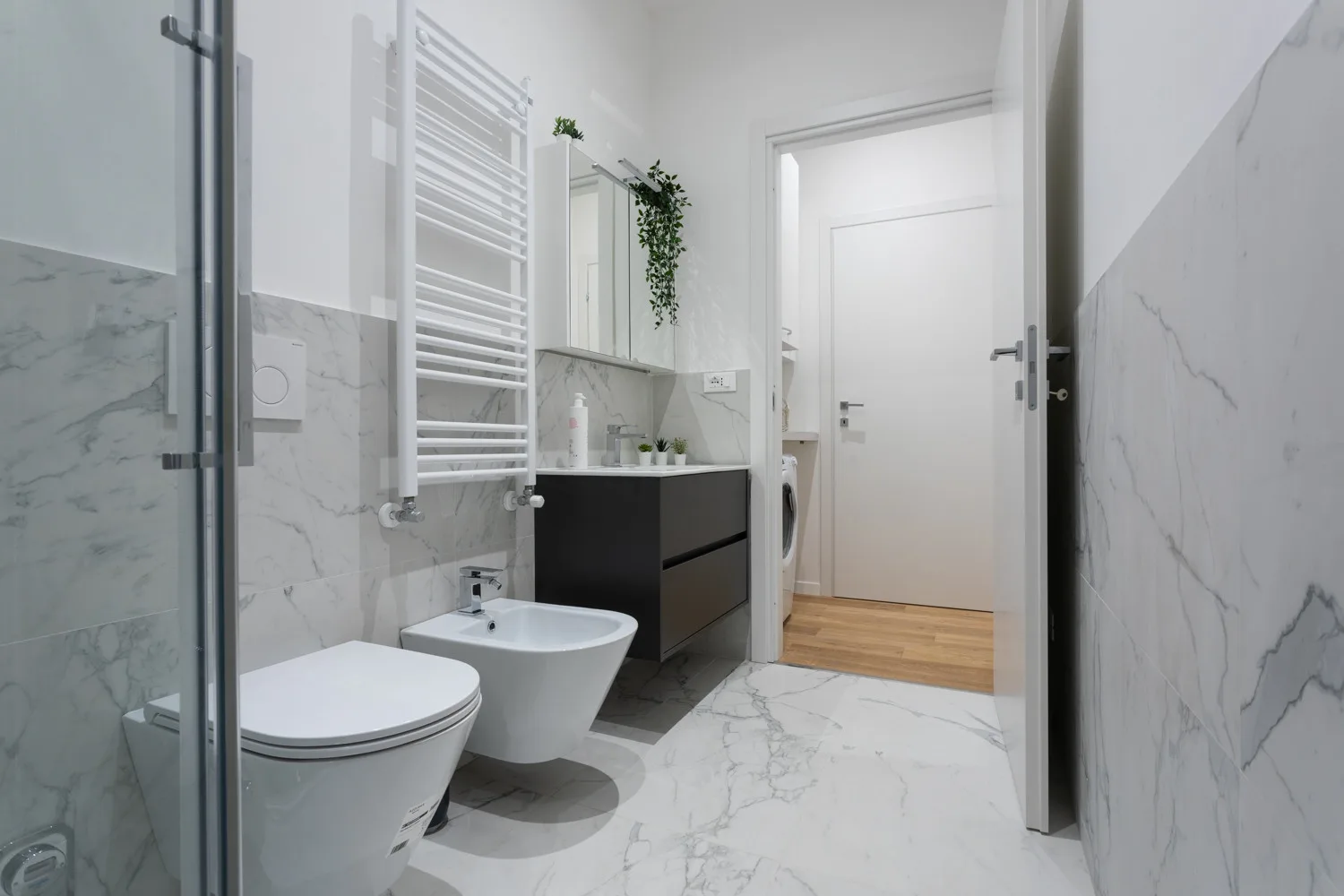 Un baño luminoso con lavabo, inodoro y ducha con mampara de vidrio.