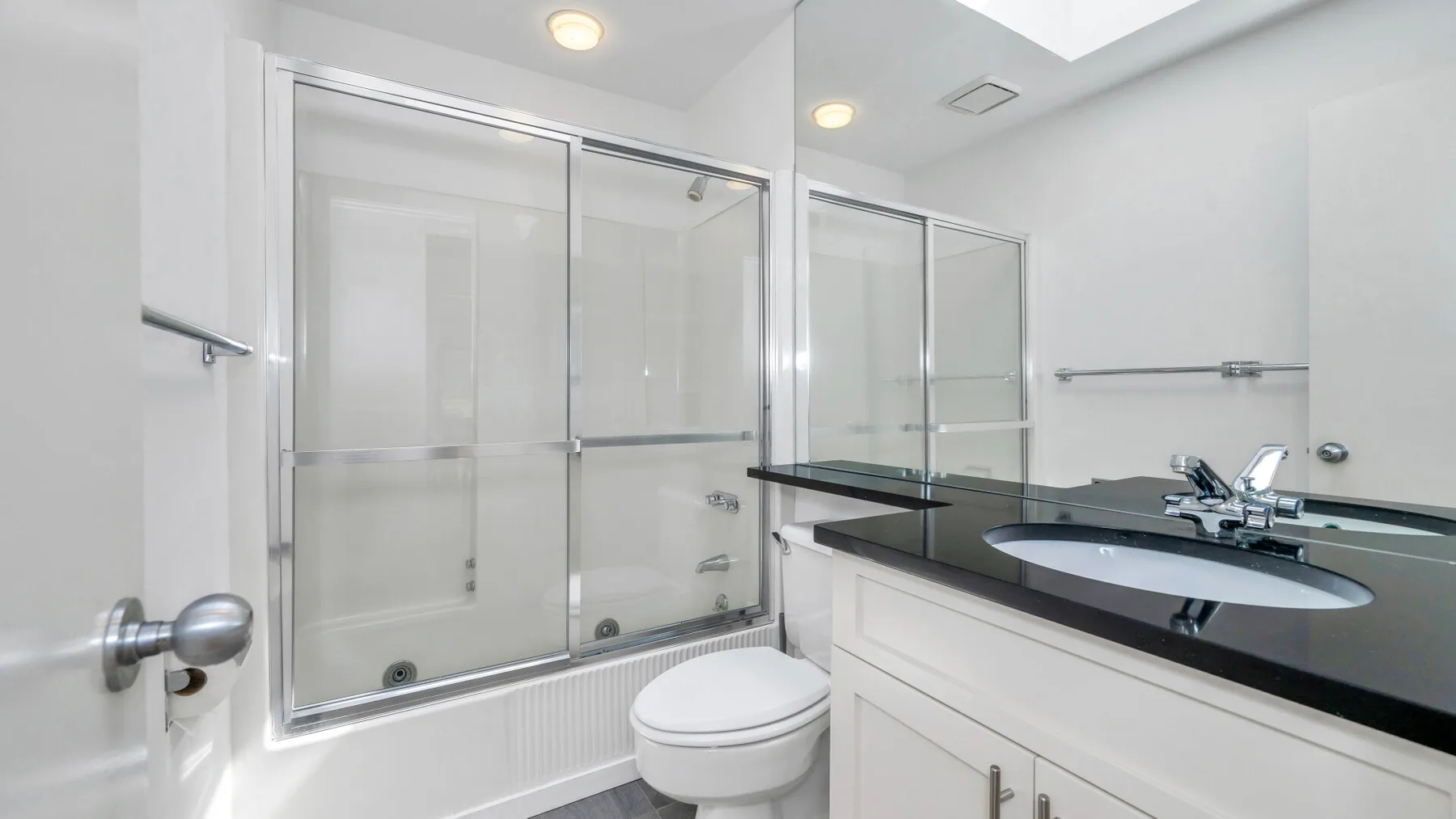 Un baño luminoso con ducha de vidrio y un lavabo con mueble.