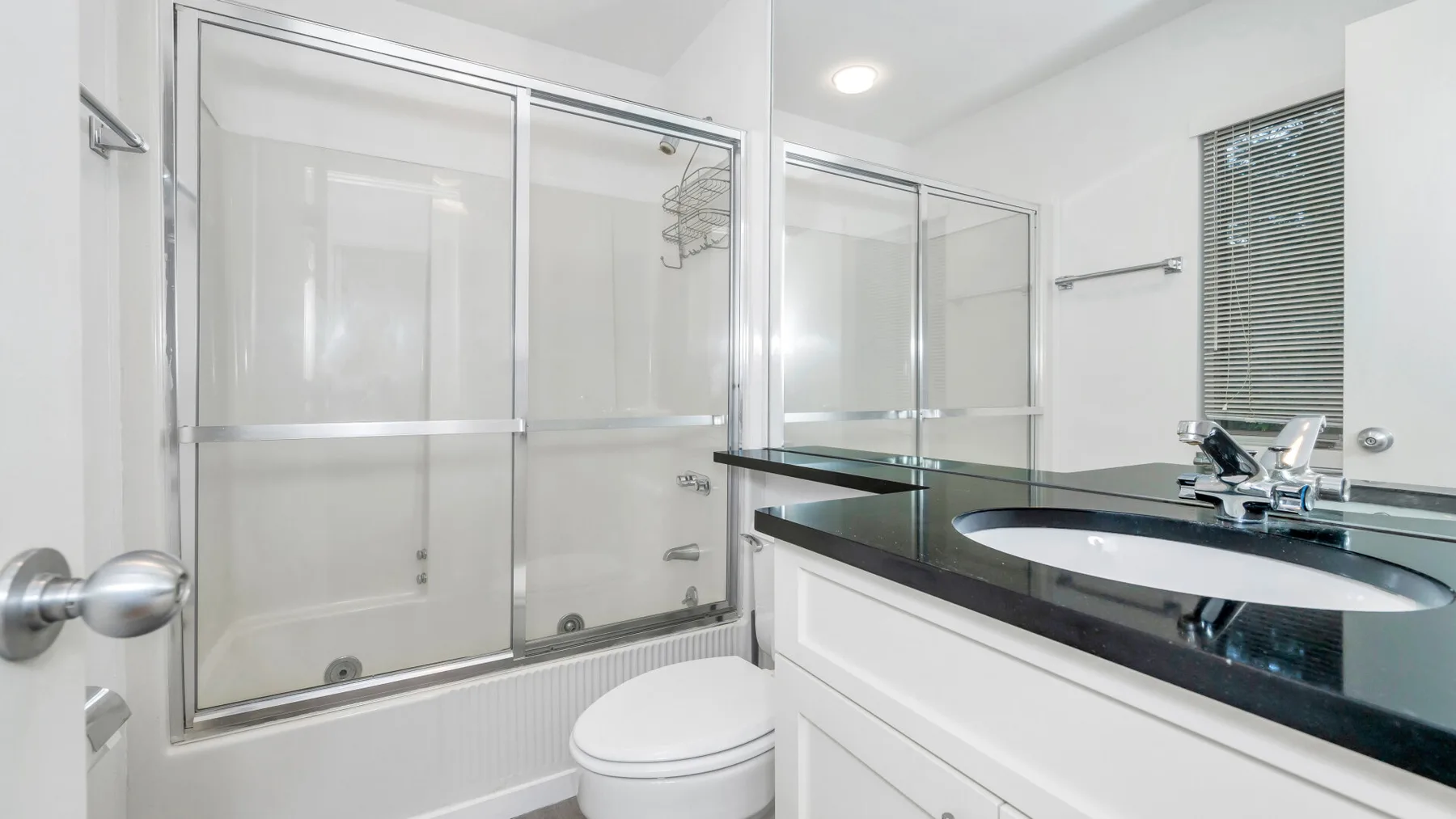 Un baño luminoso con una ducha de vidrio y un lavabo con mueble.