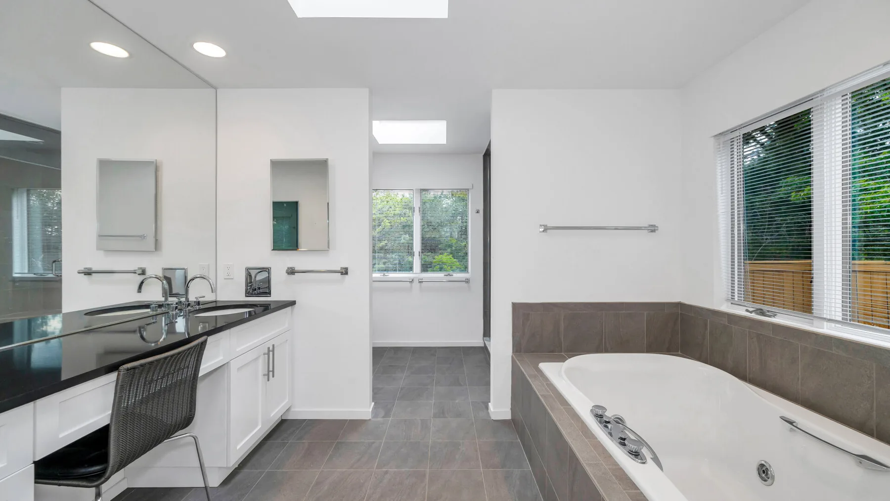 Un baño luminoso con una bañera grande, un tocador y ventanas.