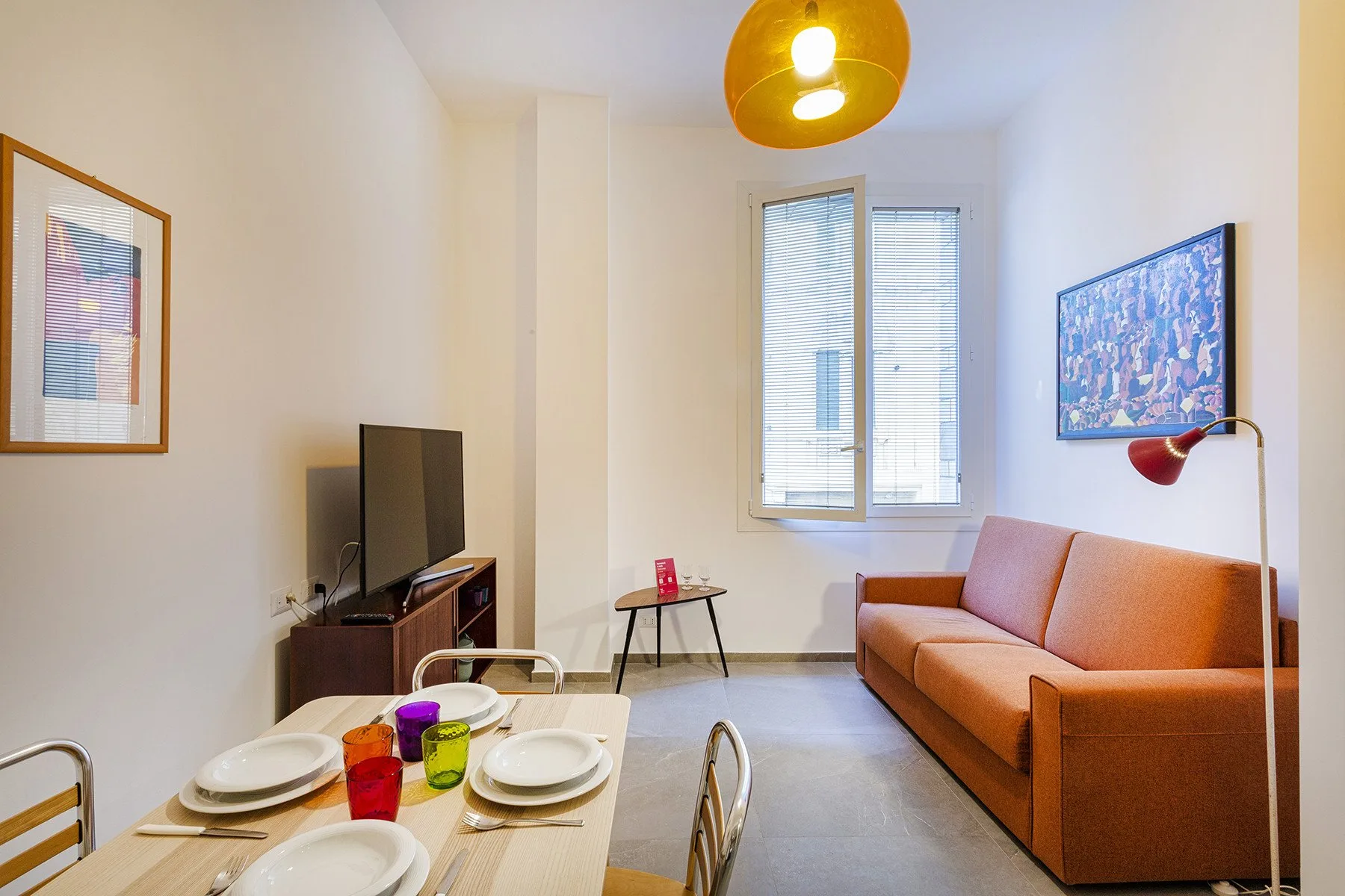 Una sala de estar con sofá, televisor y mesa de comedor.