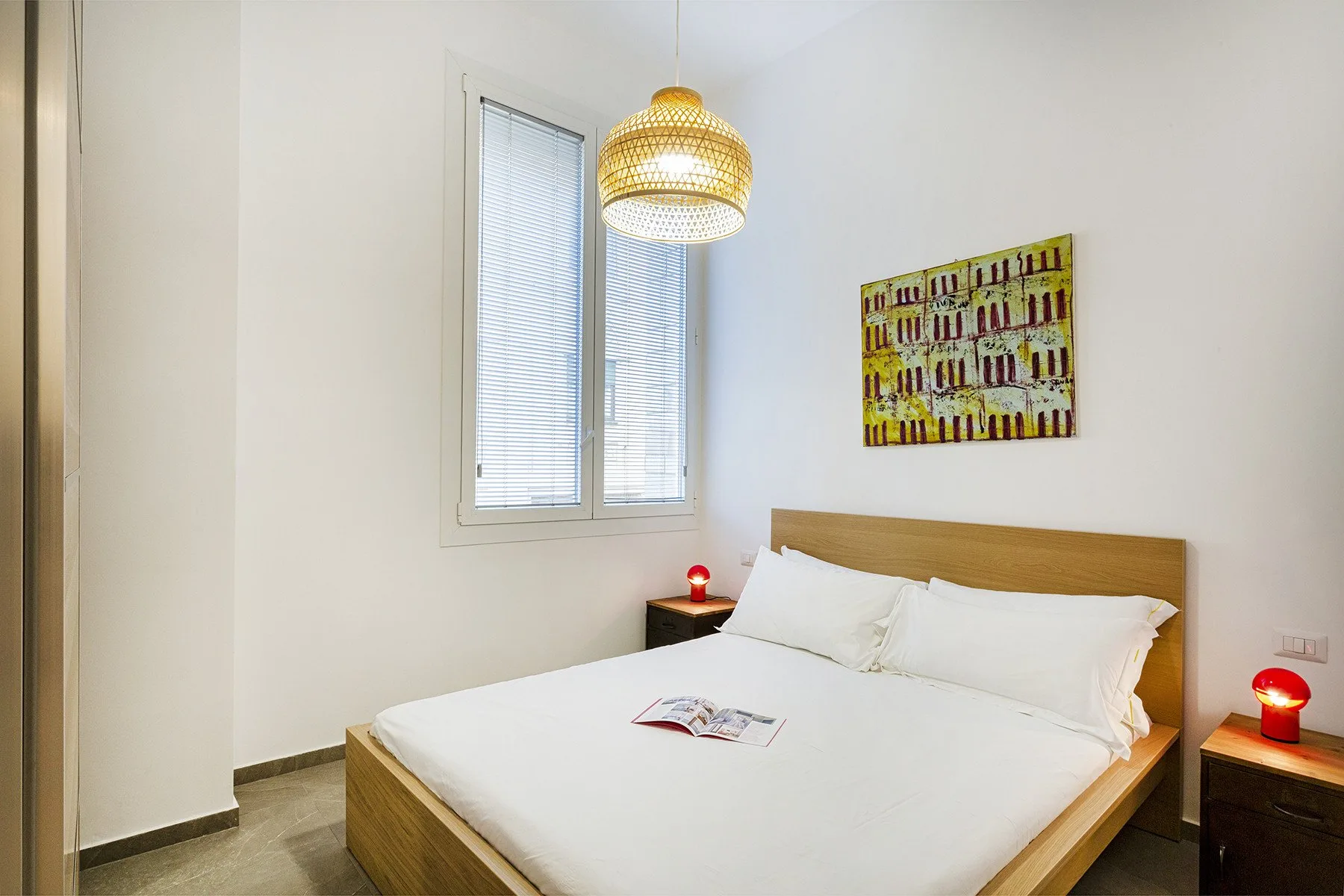 Un dormitorio con una cama bajo una ventana y una lámpara colgante.