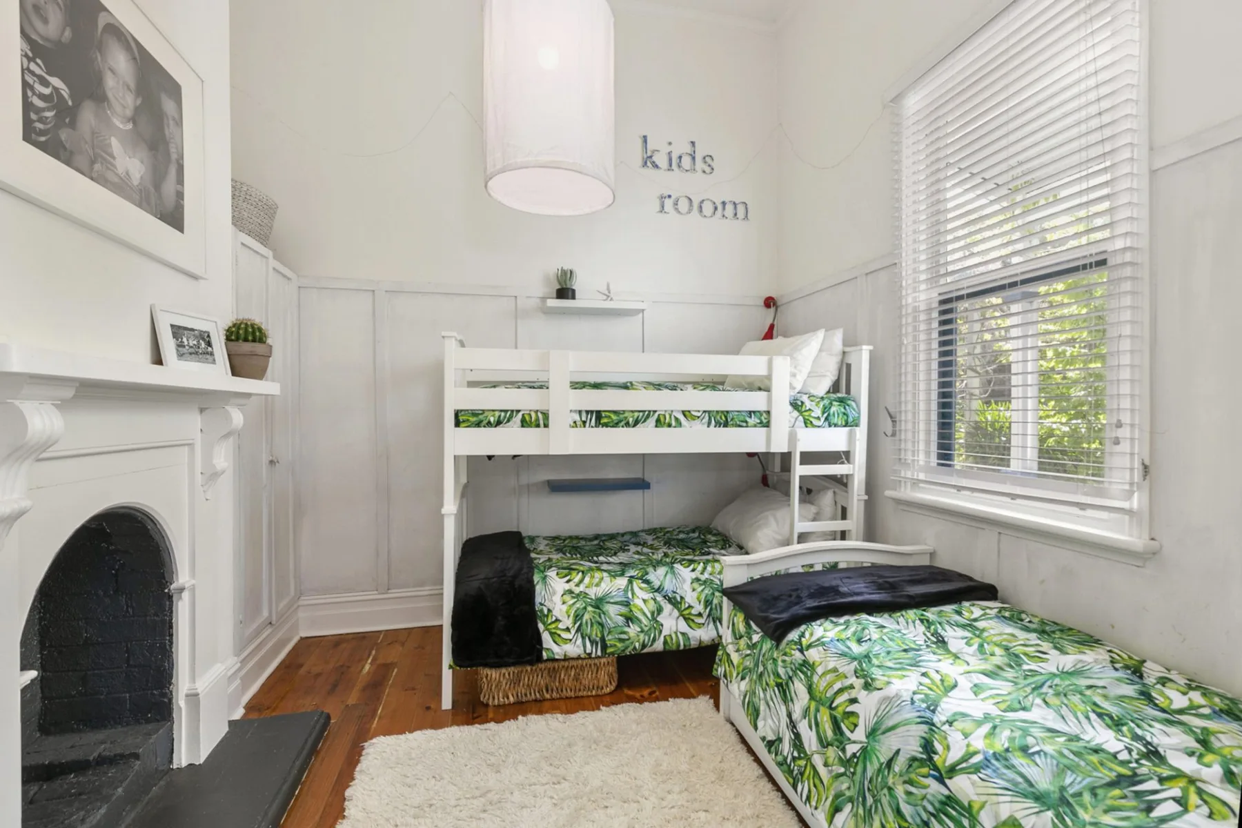 Un dormitorio luminoso con dos camas, ropa de cama de hojas y una ventana grande.