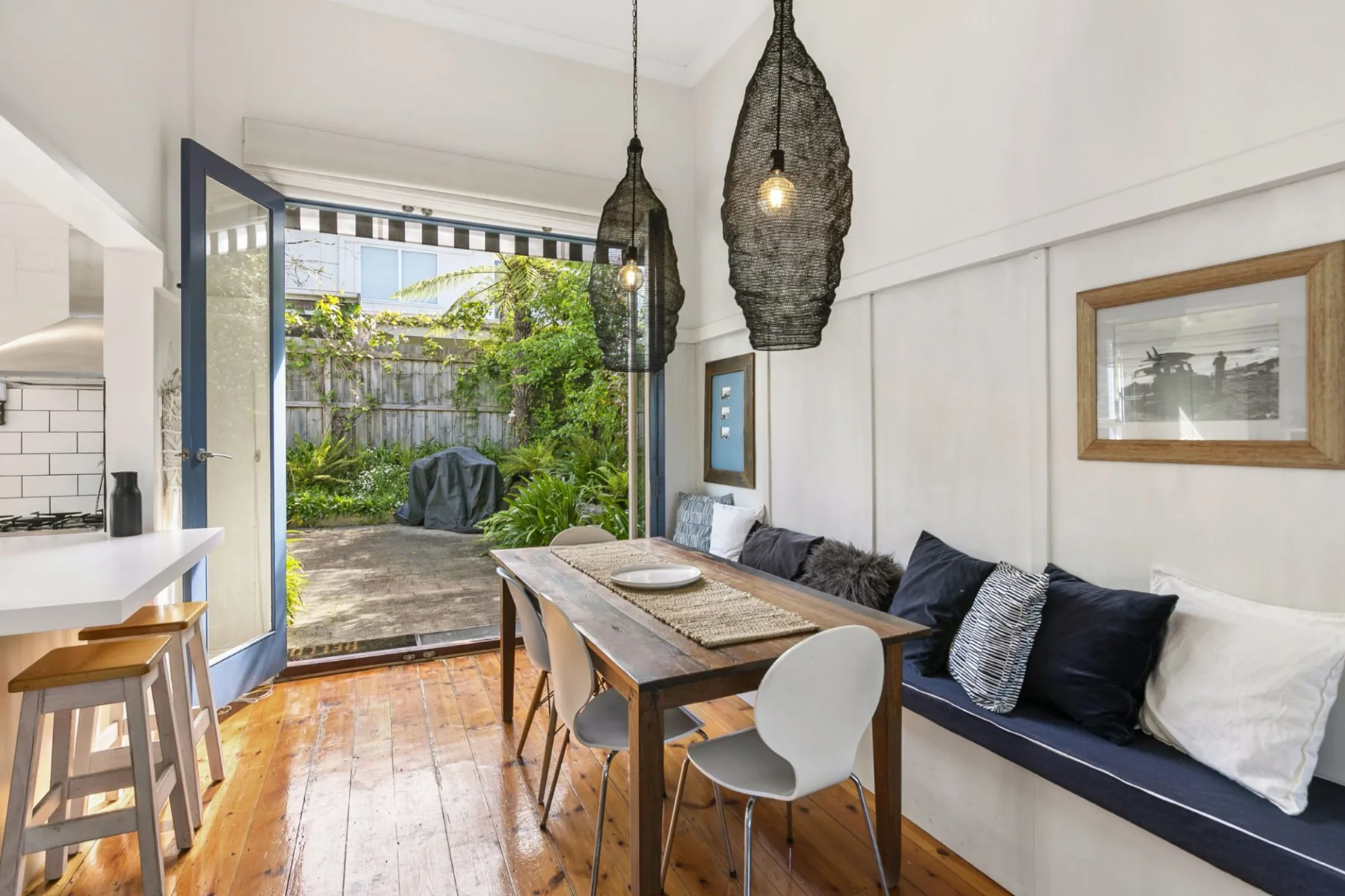 Comedor con una mesa larga de madera junto a una puerta abierta hacia un patio frondoso.
