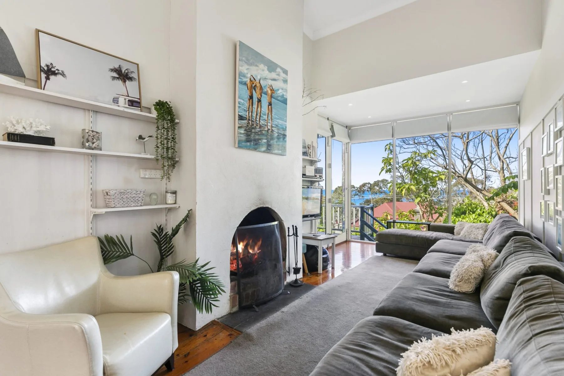 Una sala de estar luminosa con chimenea y grandes ventanas con vistas a los árboles.