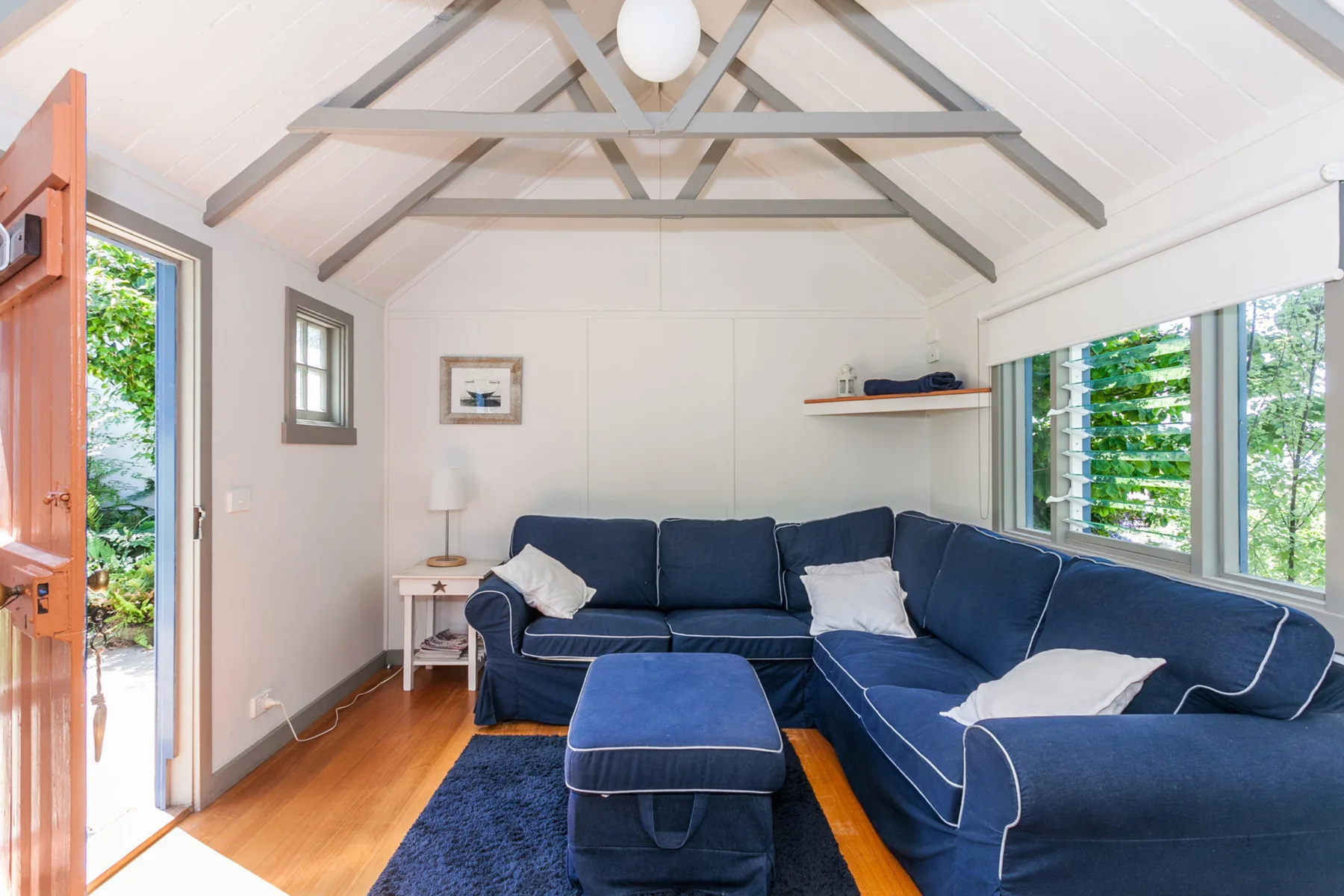 Una sala luminosa con asientos azules y grandes ventanas con vista a la vegetación.