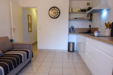 Una sala se abre a la cocina, con un sofá junto al suelo de baldosas.